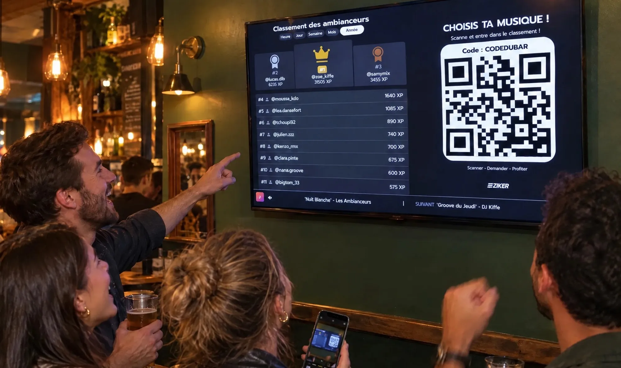Des amis dans un bar rient en montrant la TV qui affiche le Classement des ambianceurs ZIKER et son QR code, l'une d'elles le prend en photo avec son téléphone.