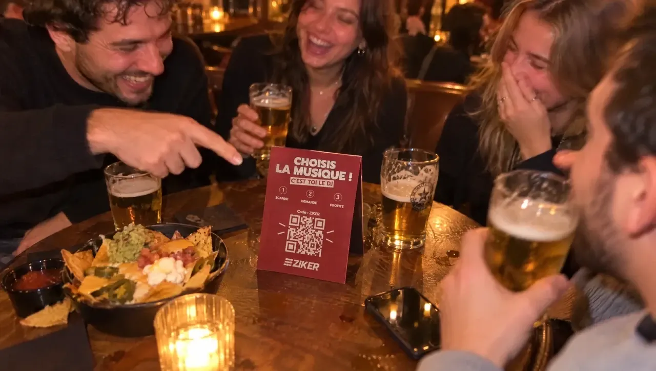 Amis attablés autour de bières et de nachos, avec le chevalet QR code ZIKER posé sur la table